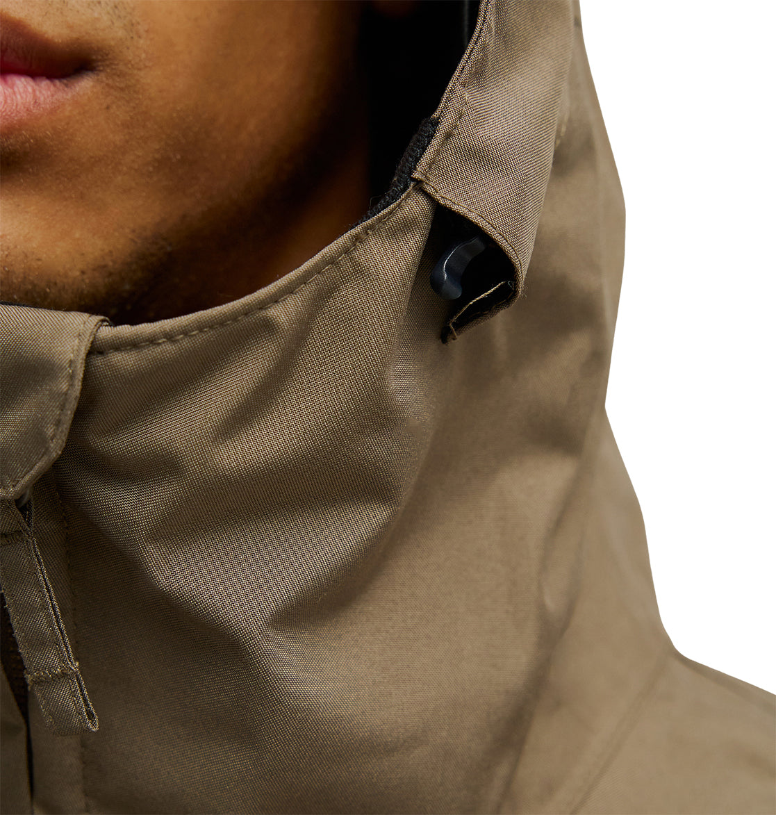 Close-up of a person wearing the DC Shoes Basis Jacket 10K in tan, featuring a high collar with a black toggle and showing the lower half of their face against a white background.