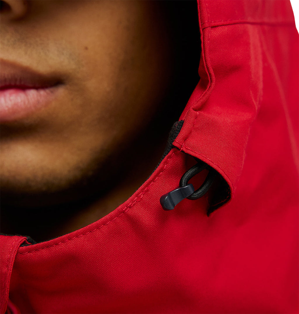 Close-up of a person’s lower face wearing the DC Shoes Basis Jacket 10K in bright red, with a black drawstring visible on the hood.