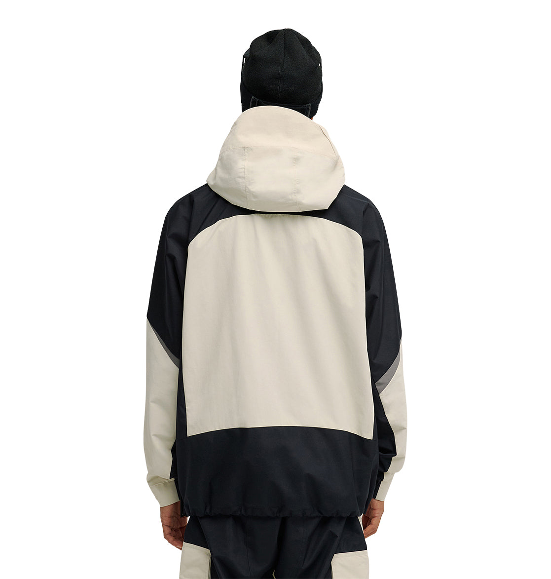 A person is shown from the back against a white background, wearing the DC Shoes Mountain Lab Anorak 10K in black and beige with the hood up, paired with a black hat.