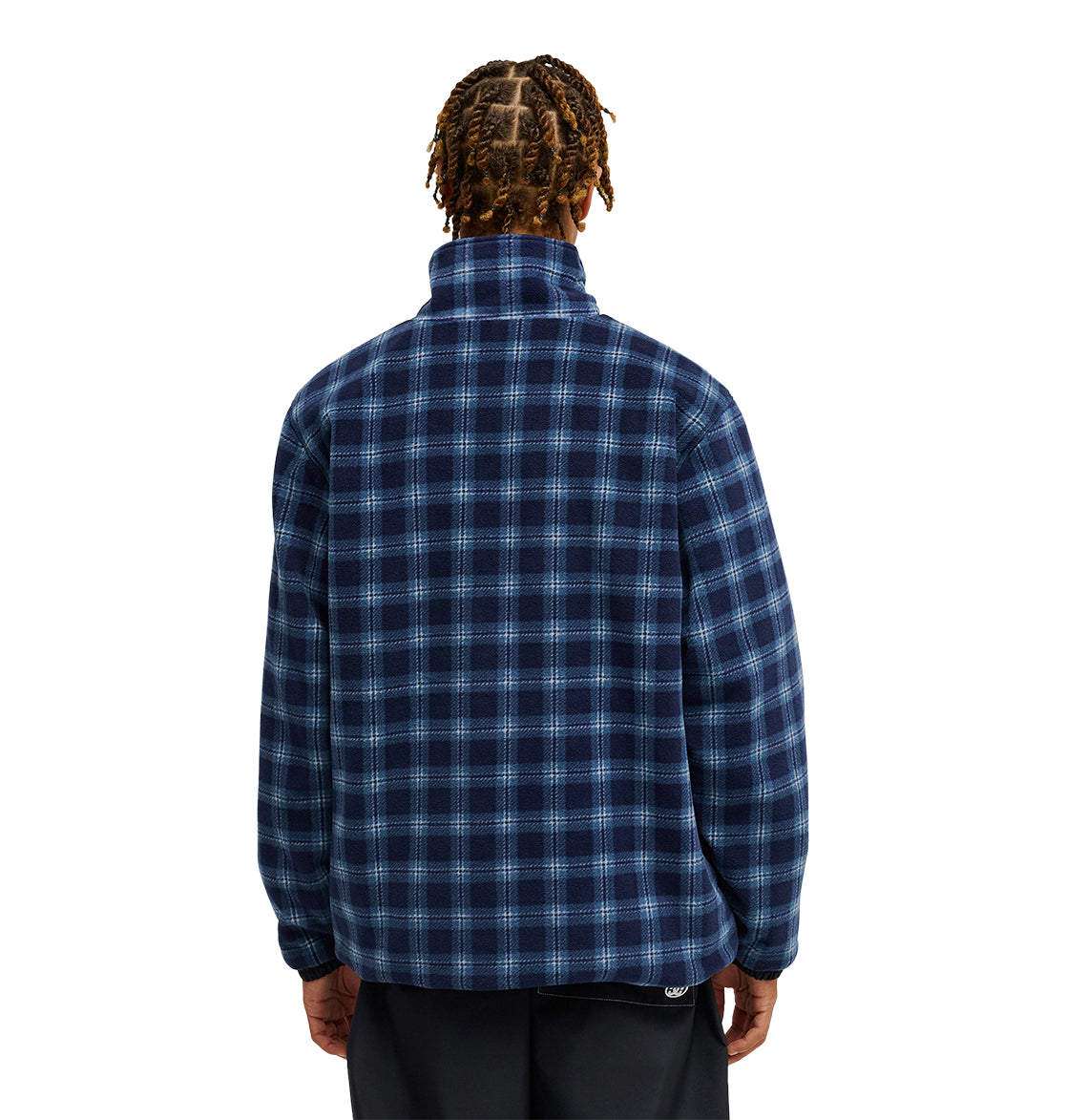 A person with braided hair is shown from the back, wearing the DC Shoes Park Reversible Anorak in blue and black plaid, paired with black pants, against a plain white background.