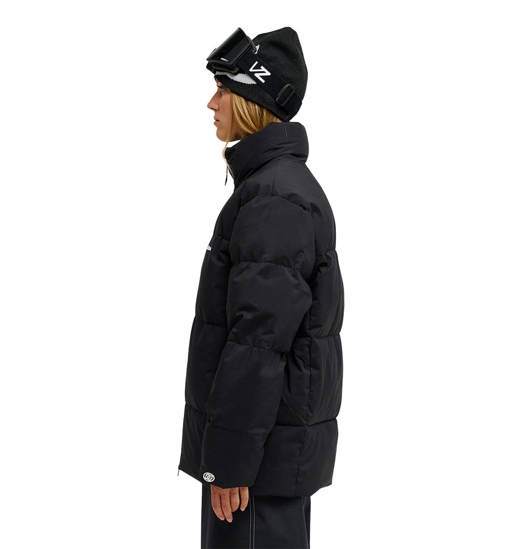 Wearing the DC Shoes Trackstar Puffer 10K jacket, along with black pants, a black beanie, and ski goggles, a person stands in profile against a white background—ready for peak snow performance with breathable protection.