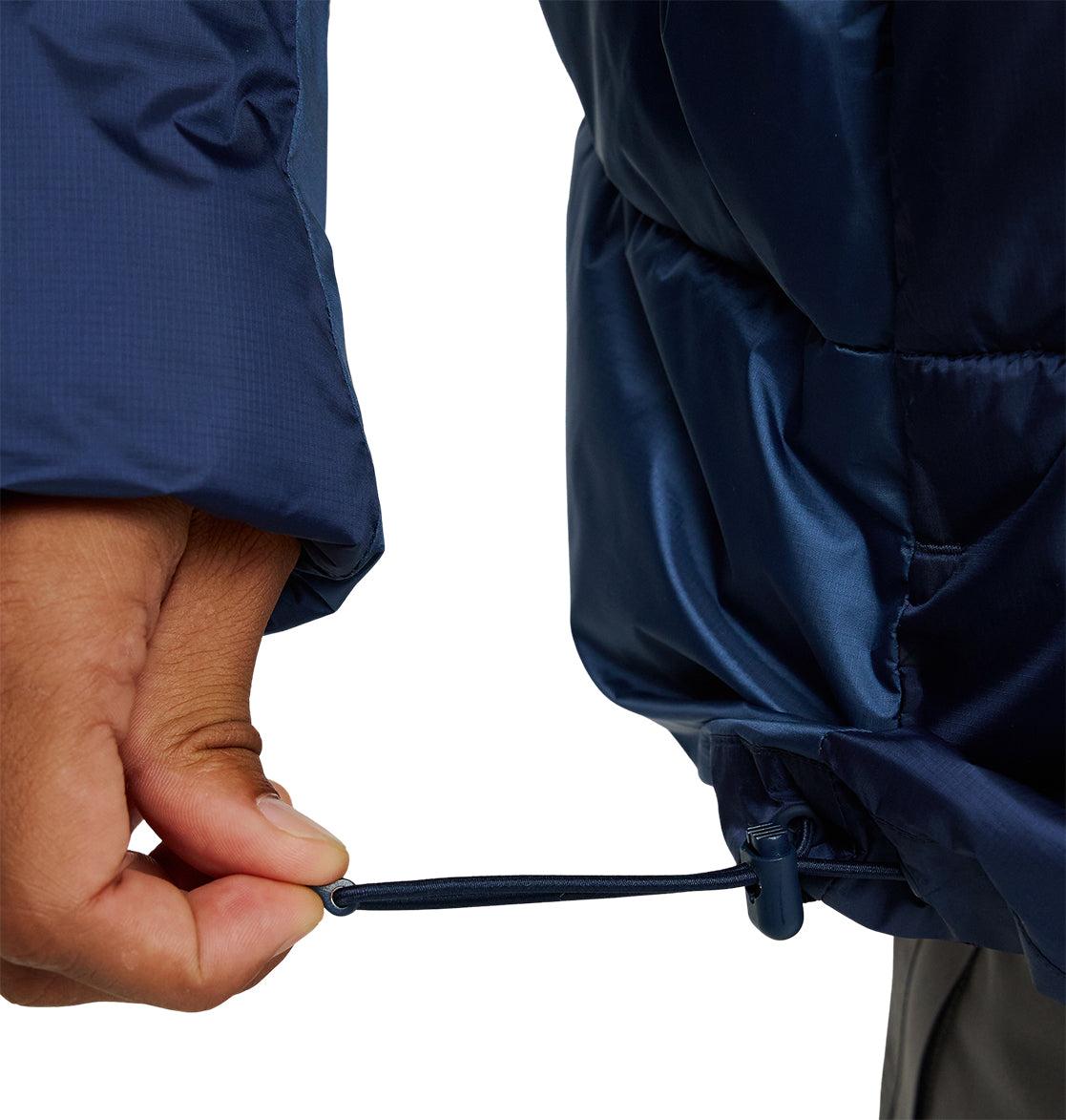 Wearing the DC Shoes Powder Puffer 10K, a person pulls the adjustable drawcord on the hem of this navy blue jacket, securing it around the waist for improved insulation and snow performance.