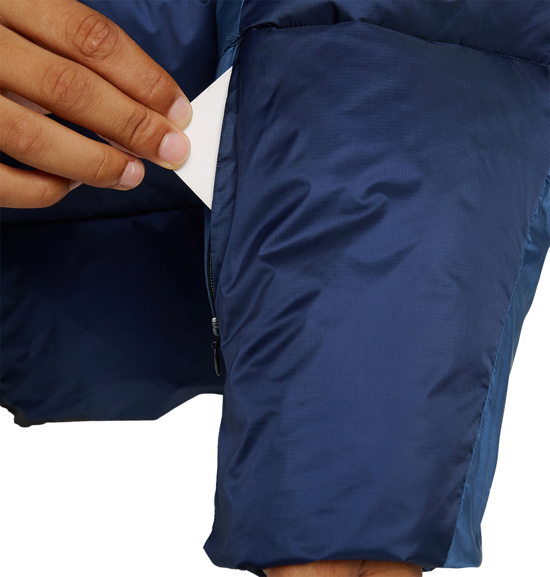 A hand places a white card into the zippered pocket of the DC Shoes Powder Puffer 10K jacket, showcasing its excellent insulation and reliable snow performance.