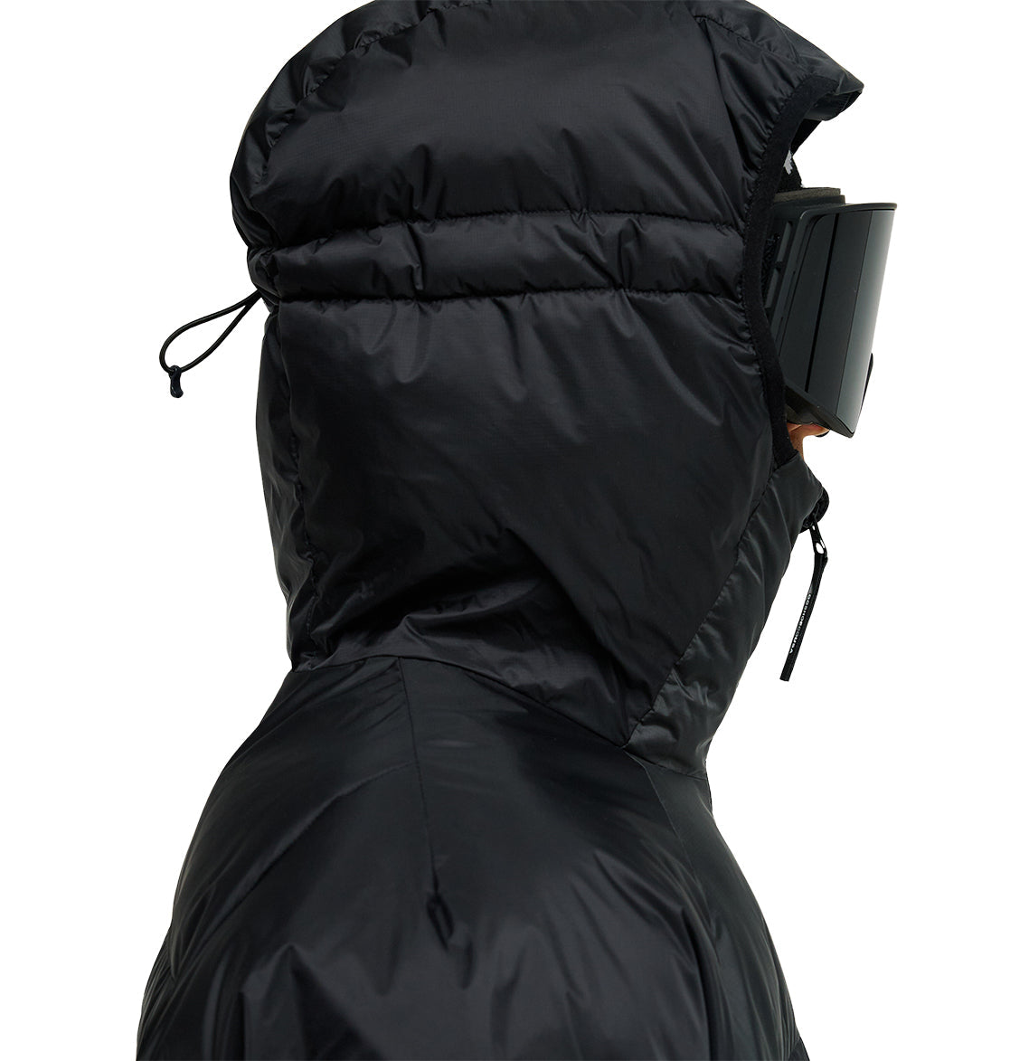 A person wearing the DC Shoes Powder Puffer 10K jacket, featuring a hood for breathable protection, paired with black ski goggles. Side profile view against a plain background.