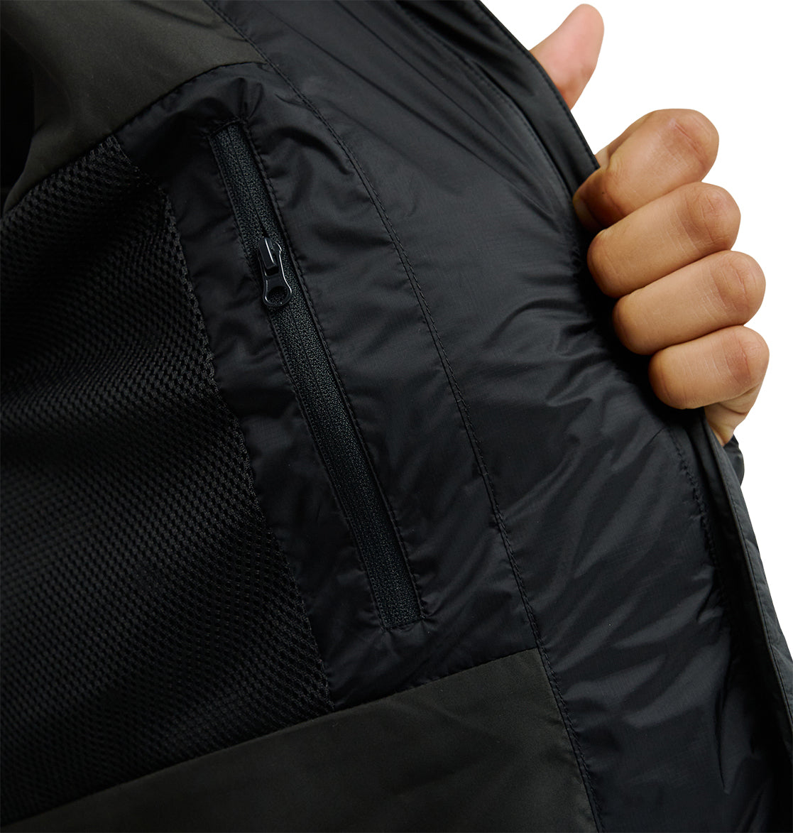 A hand holds open the DC Shoes Powder Puffer 10K jacket, revealing its inner zippered pocket and breathable mesh lining engineered for superior snow performance.