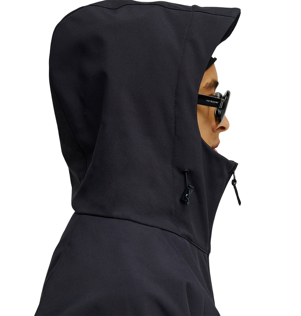 A person wearing a black DC Shoes Spectrum Softshell Jacket and black sunglasses is shown in profile against a plain background. The DC Shoes jacket, recognized for its breathable protection and waterproofing, is fully zipped with the hood pulled up to cover most of the head.