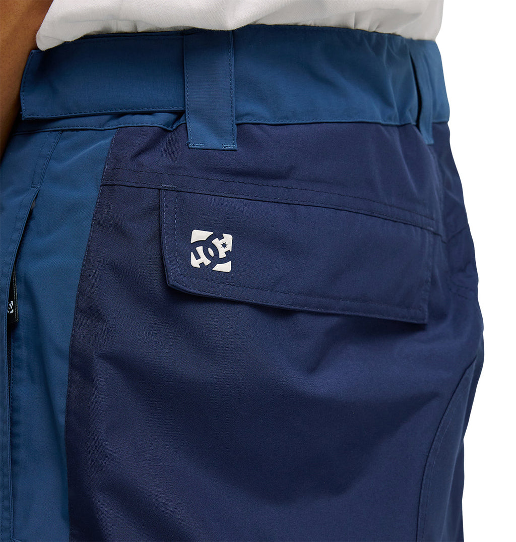 Close-up of a person wearing DC Shoes Mountain Lab Pants 10K in blue, featuring a rectangular flap pocket with a small white DC logo. The breathable fabric of these pants ensures comfort during active days outdoors.
