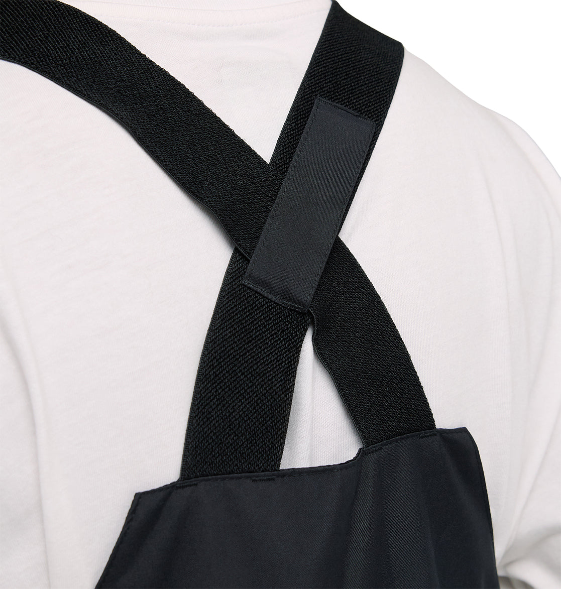 Close-up of a person wearing a white shirt and the DC Shoes Docile Bib 10K—featuring cross-back straps and an insulated design for enhanced protection and comfort.