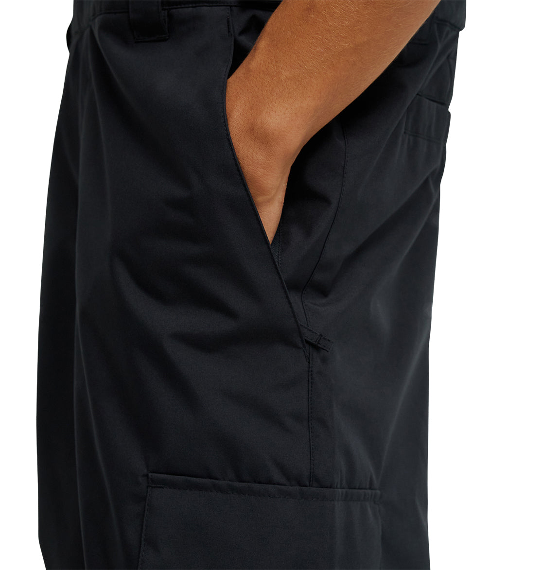 A person wearing DC Shoes Docile Bib 10K black insulated bib pants, with their right hand in the pocket. The image shows a close-up side view from the waist to mid-thigh.