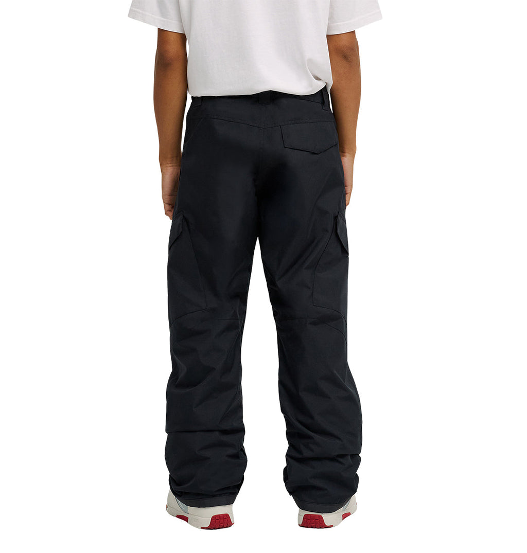 A person is shown from the waist down, wearing a white t-shirt and DC Shoes Banshee Pants—black cargo pants with waterproof insulation—paired with gray and red sneakers. Their back faces the camera.