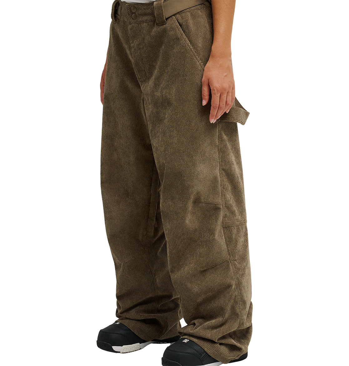 A person wearing loose-fitting, brown DC Shoes Snow Carpenter Pant 10K, designed for weather protection and enhanced venting, paired with black shoes and standing with their arms relaxed by their sides. The focus is on the pants and lower body.