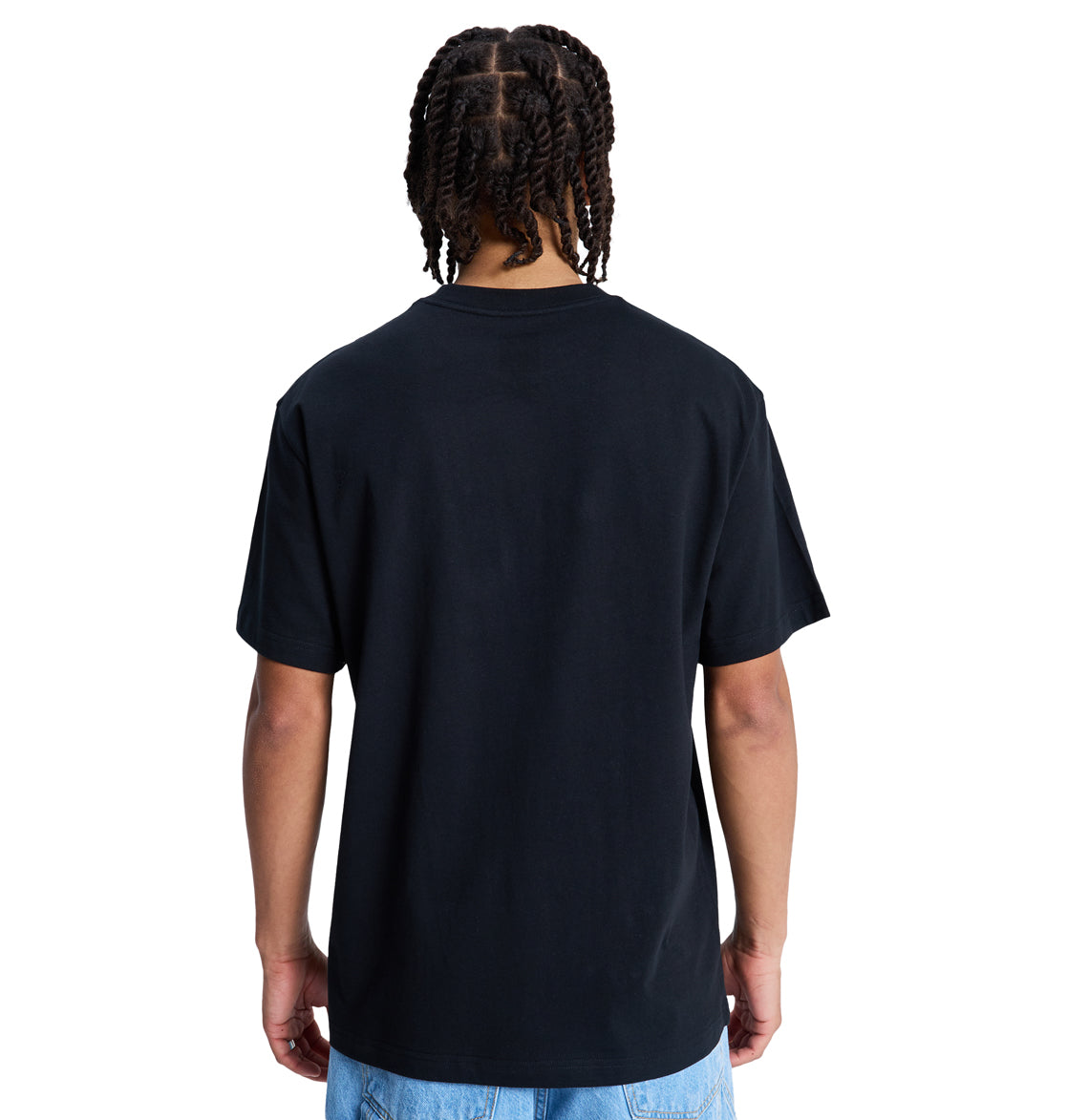 A person with braided hair is seen from the back, wearing a Reebok DC Star Oxidized Hss plain black t-shirt and light blue jeans against a white background.
