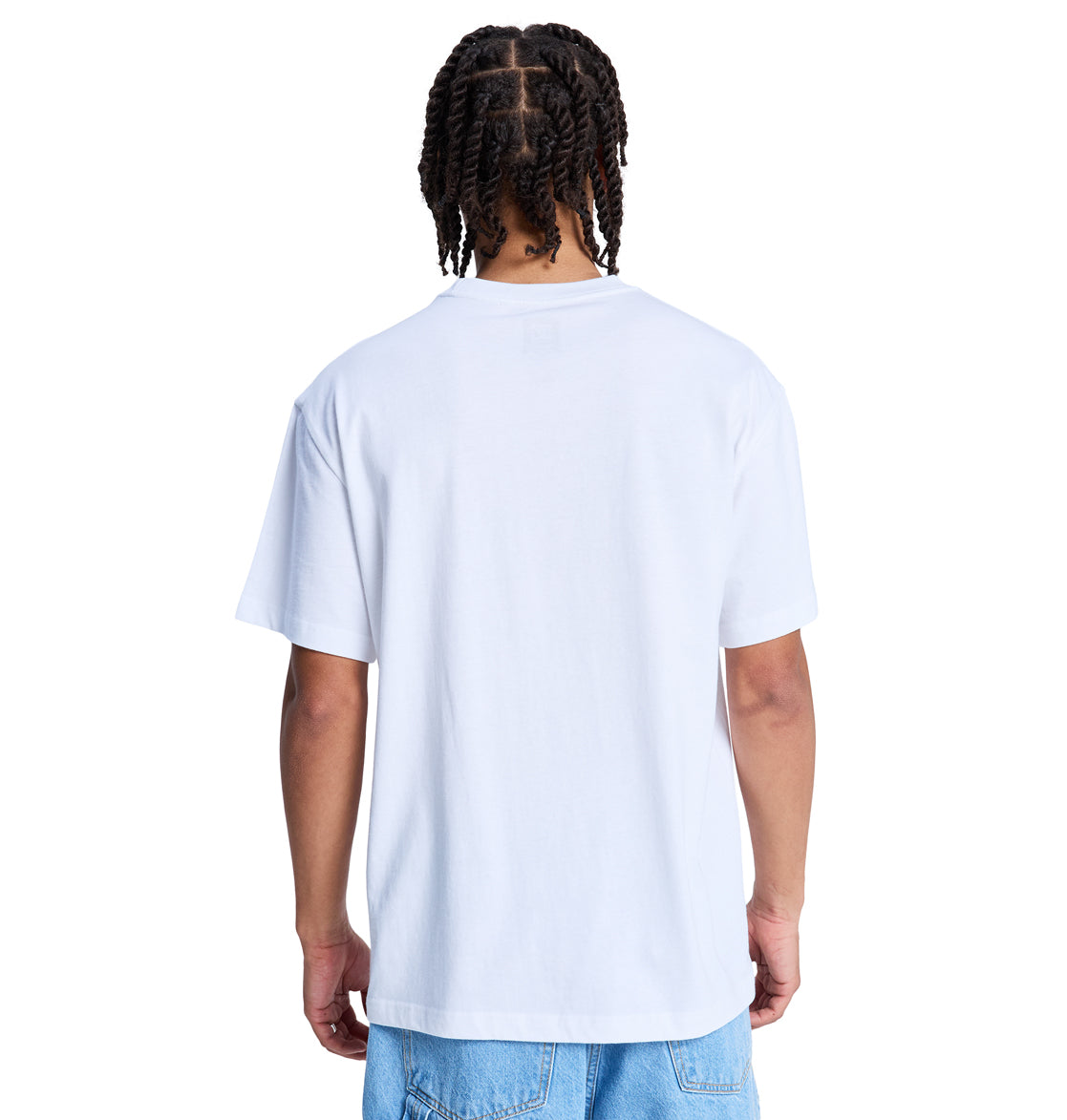 A person with braided hair is shown from the back against a white background, wearing the Reebok DC Star Oxidized Hss T-shirt and light blue jeans.