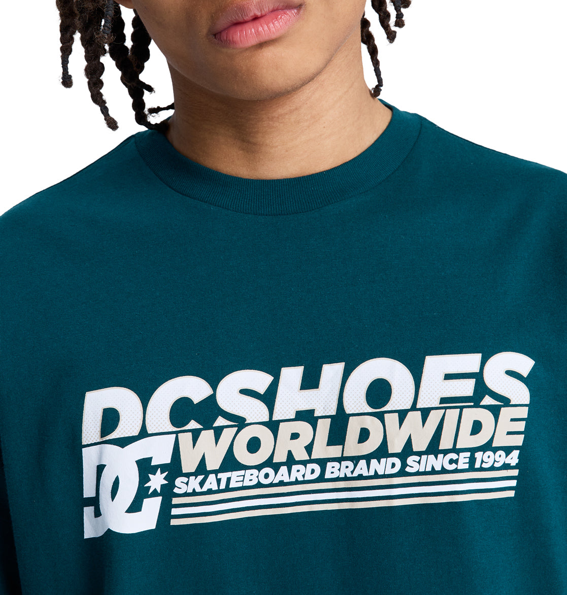 A person wearing a teal Reebok Queltra Lhss t-shirt; only the lower half of their face and upper torso are visible.