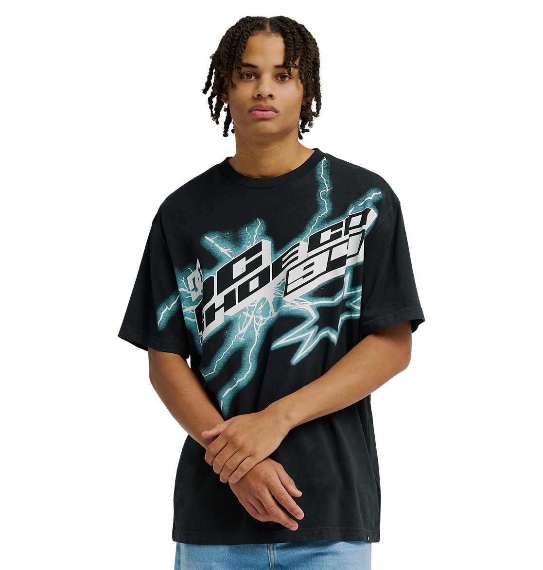 A man with short dreadlocks stands against a plain light background with his hands clasped in front, wearing the Men's DC Star Struck Tee by DC Shoes—a relaxed fit black skate shirt featuring bold, abstract white and teal graphics reminiscent of star struck artwork.