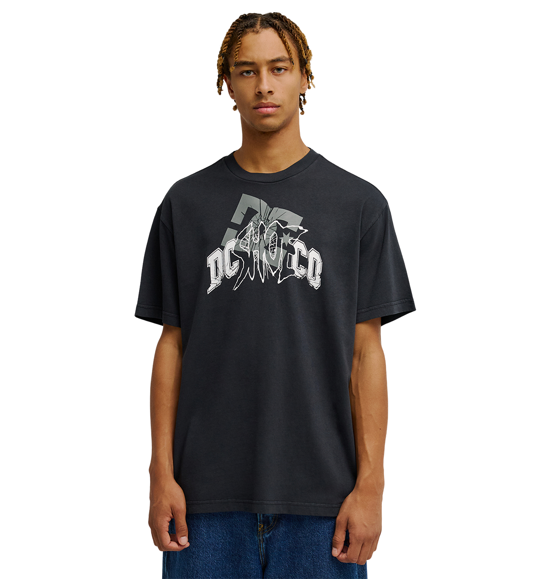 A person with braided hair wears the Men's DC Speratic Tee by DC Shoes—a relaxed fit black graphic skate t-shirt with a bold white logo—paired with blue jeans, standing against a plain white background.