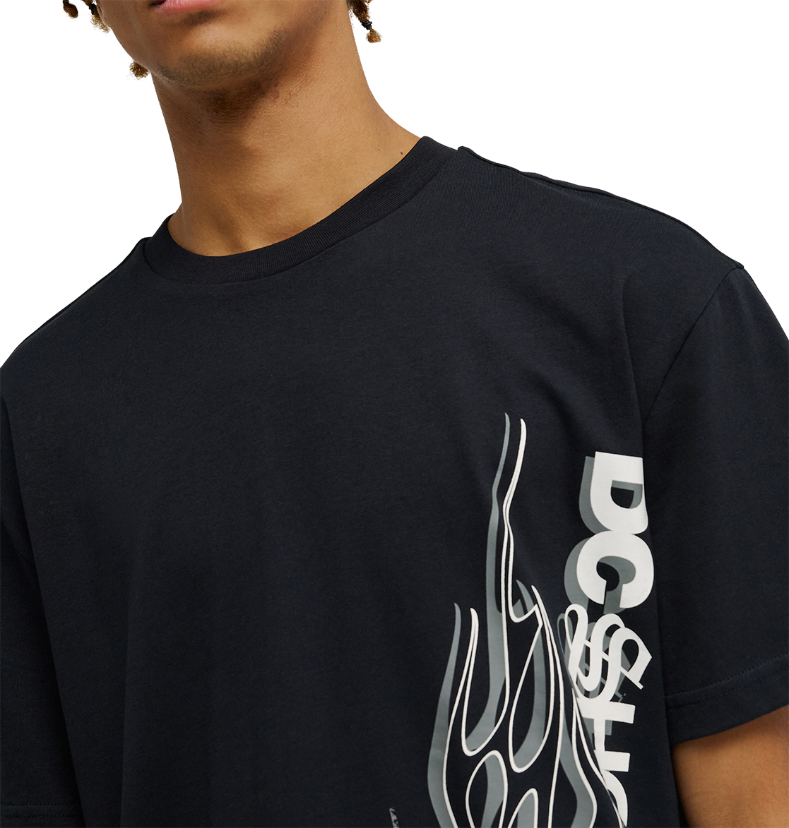 A person wearing the Men's DC Side Flame Tee by DC Shoes—a black graphic tee with a bold white stylized flame design and "DC SHOE" text on the front—shown from shoulders to mid-chest, perfect for skate sessions or showing off striking DC artwork.