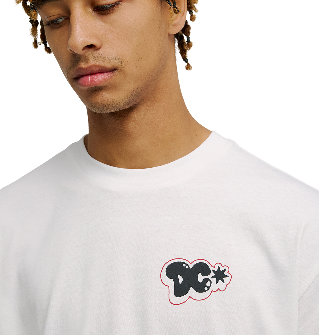 A person wearing the Men's DC Side Flame Tee by DC Shoes, a white graphic skate shirt with a small black and red-outlined DC Shoes logo on the chest. The tee has a relaxed fit, and the person is looking down with a neutral expression.